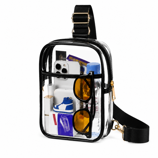 Clear crossbody bag with black trim and gold hardware filled with a phone, sunglasses and shoes