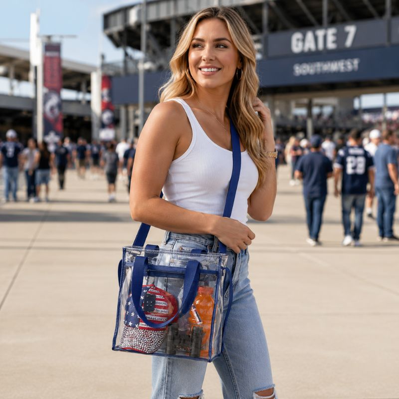 Woman wearing a navy-trim clear crossbody tote while walking outside an event venue.