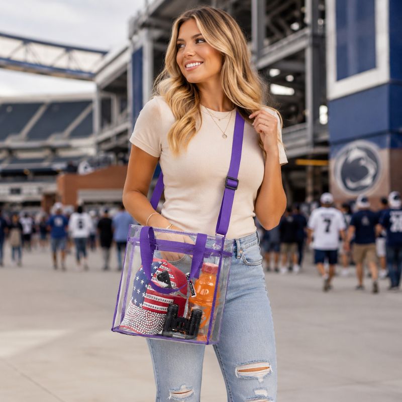 Woman carrying a purple-trim clear crossbody tote outside an event venue.
