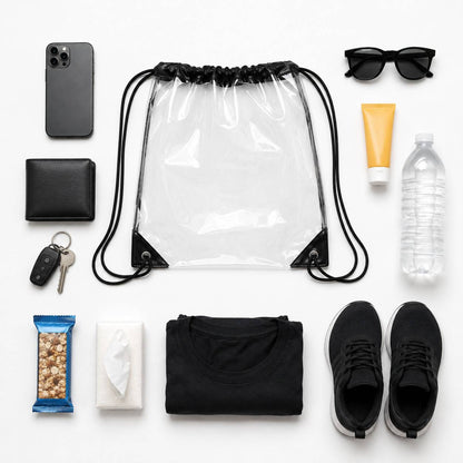 Top-down flatlay of the clear drawstring backpack bag surrounded by a phone, wallet, keys, sunglasses, and snacks.