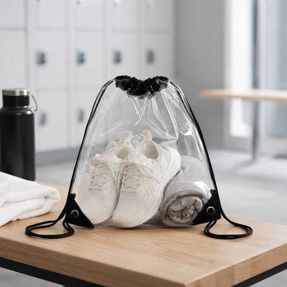 Clear drawstring backpack bag holding sneakers and a folded towel in a gym locker room.
