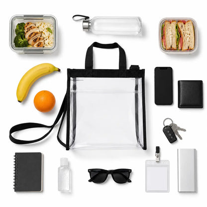 Clear lunch bag tote laid flat beside a water bottle, fruit, phone and sunglasses