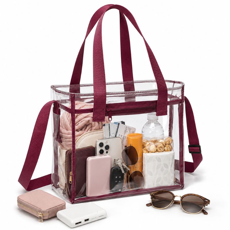 Burgundy-trim clear stadium tote packed with a smartphone, wallet, keys, sunglasses, water bottle, and small personal items.