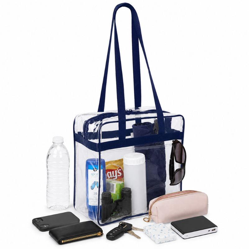 Clear stadium tote with navy trim packed with a water bottle, chips, sunscreen, sunglasses, and a coin pouch.