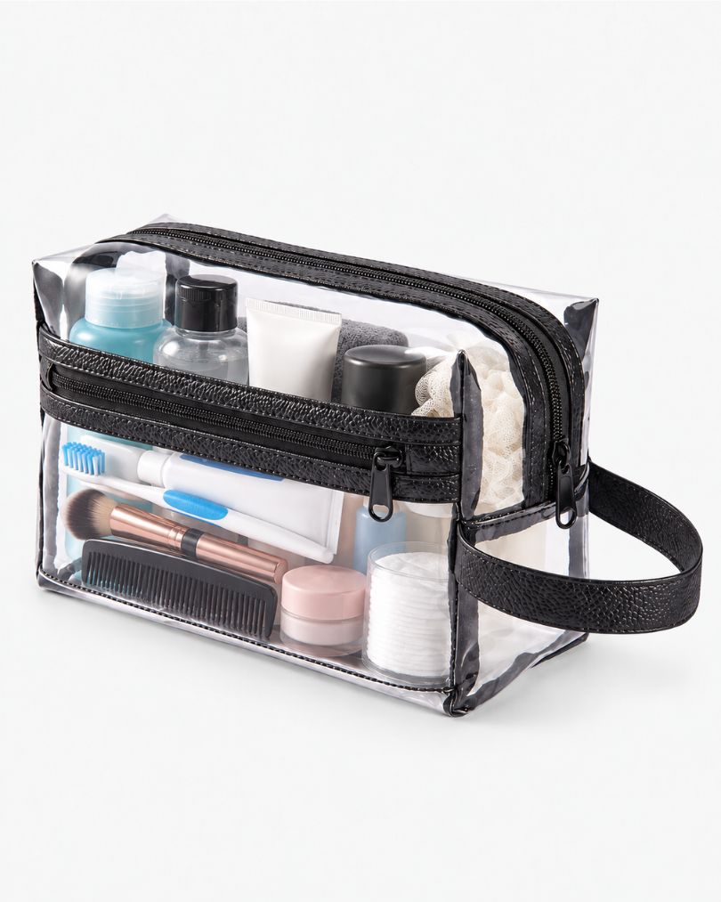 Clear toiletry bag packed with travel bottles, a lotion tube and a shower pouf in the main compartment, plus a toothbrush, makeup brush, comb and cotton pads in the front zip pocket.