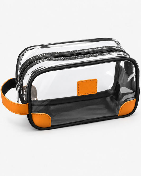 Clear travel toiletry bag with orange trim, black fabric base, top zipper and side carry strap, shown empty on a white background.