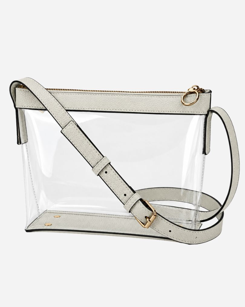 White clear crossbody purse with vegan leather trim, black edge piping and gold-tone zipper, empty, in a three-quarter view